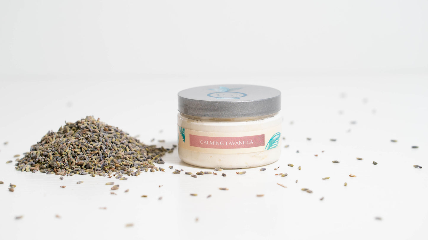 A 4 oz. jar of LaVanilla body butter is displayed against a white background, accompanied by lavender buds placed beside it, highlighting the product's luxurious vanilla essence complemented by the soothing presence of lavender.